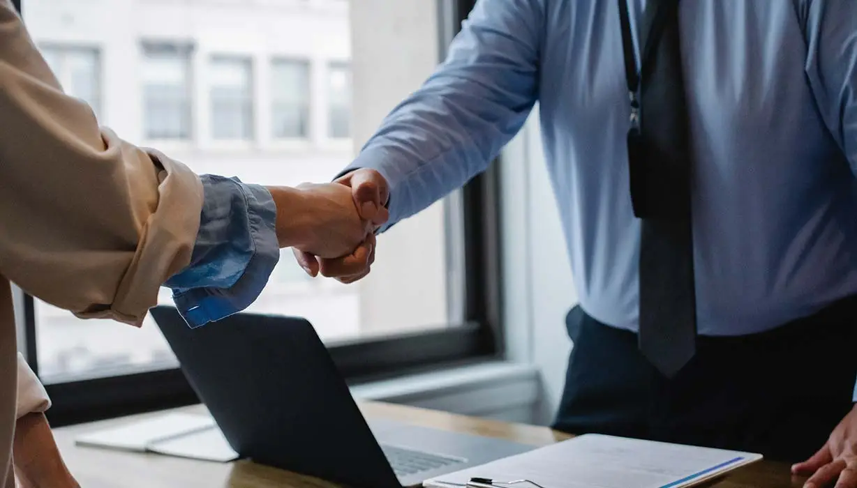 two people shaking hands over a desk