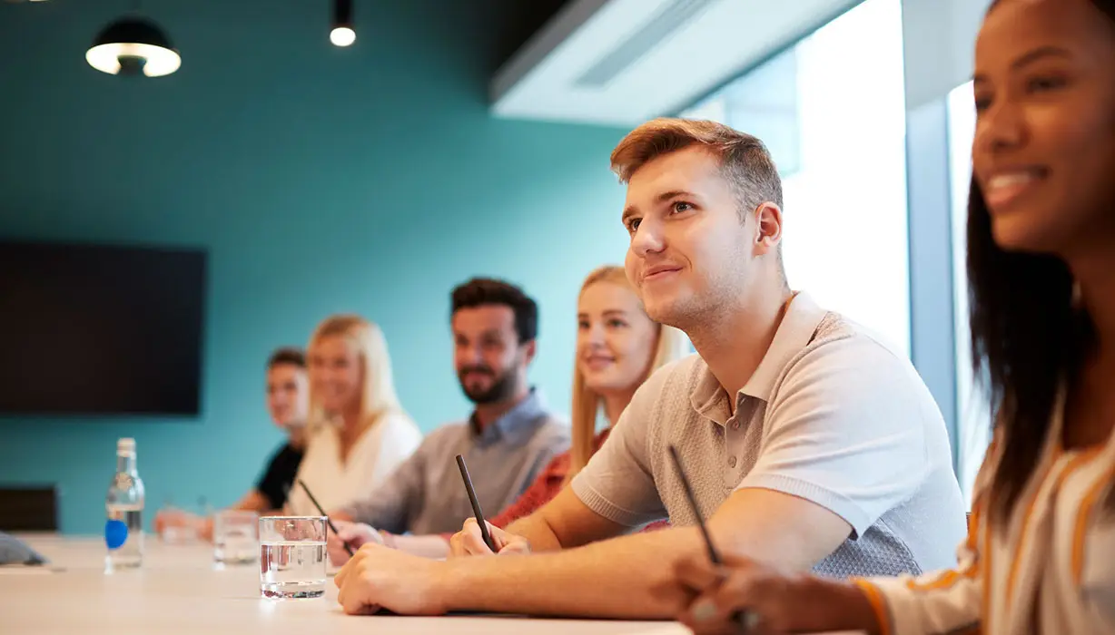 group of people sitting at a table in a meeting