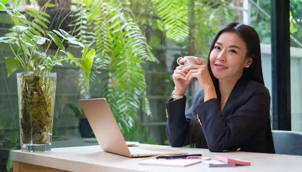 smiling Asian woman sitting at table holding a cup