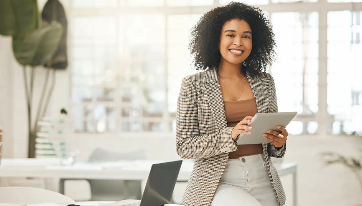 smiling woman holding a tablet in a modern office