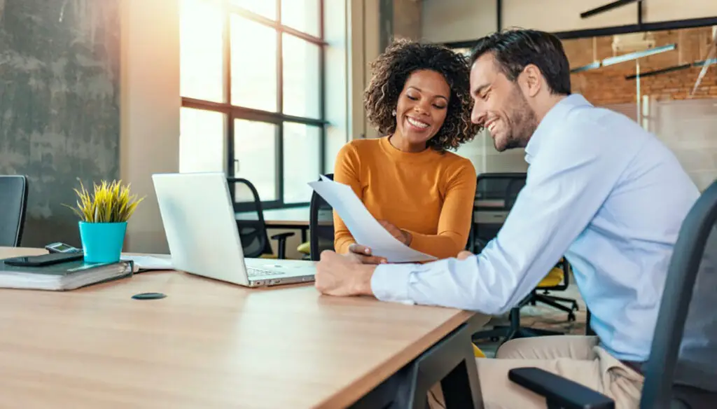 smiling man and woman in an office looking at paper
