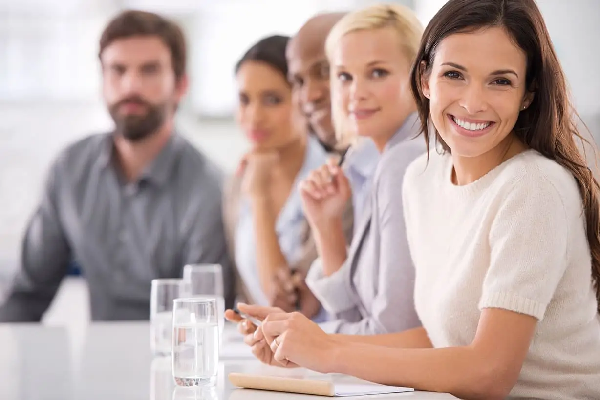 five people in a meeting sitting at a table.