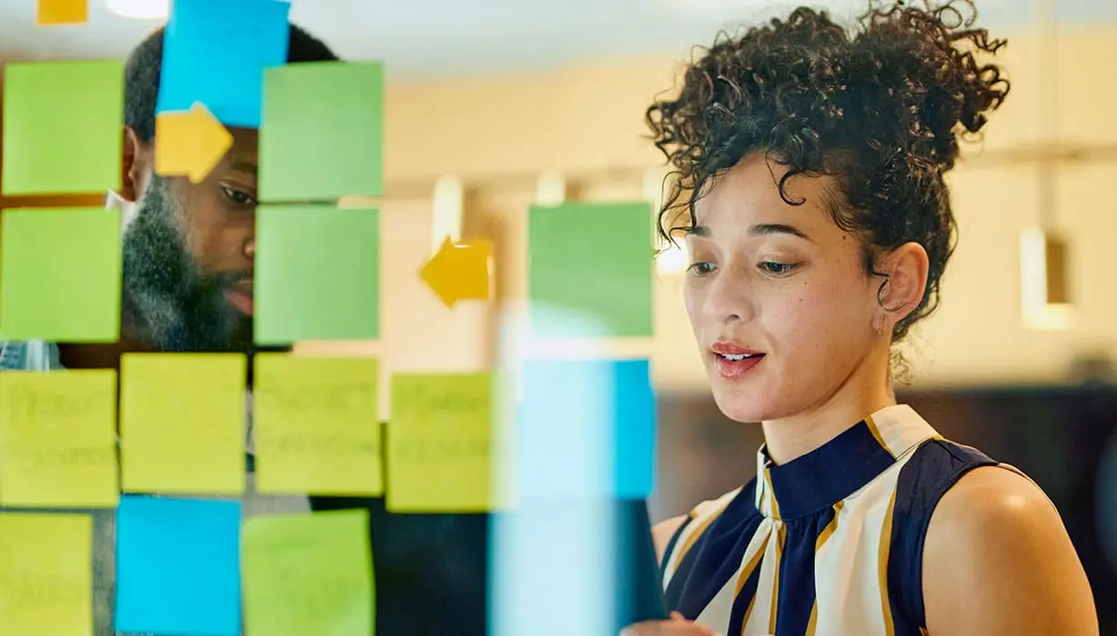 girl standing in front of a clear board with post-it notes