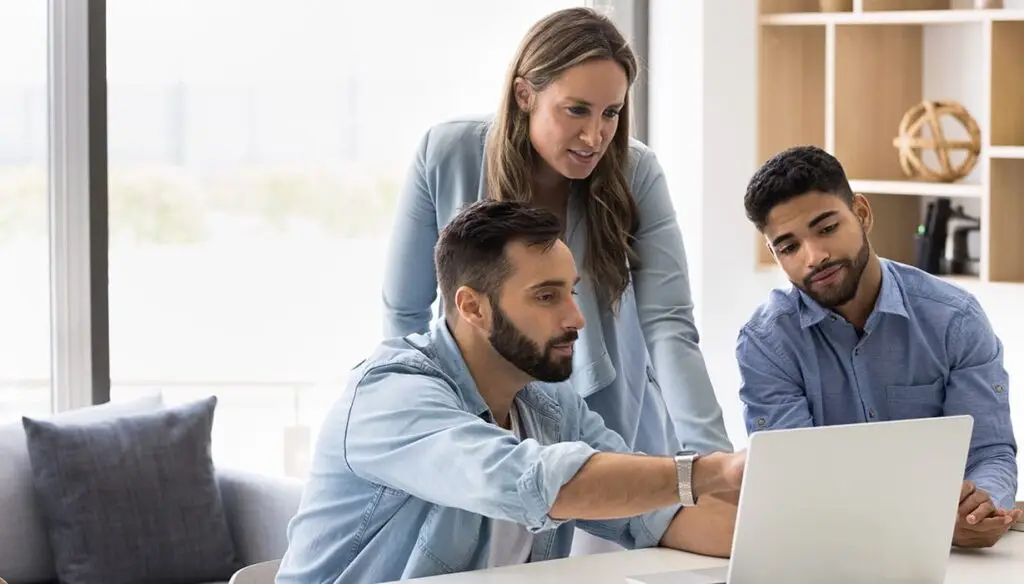 three people in an office looking at a laptop